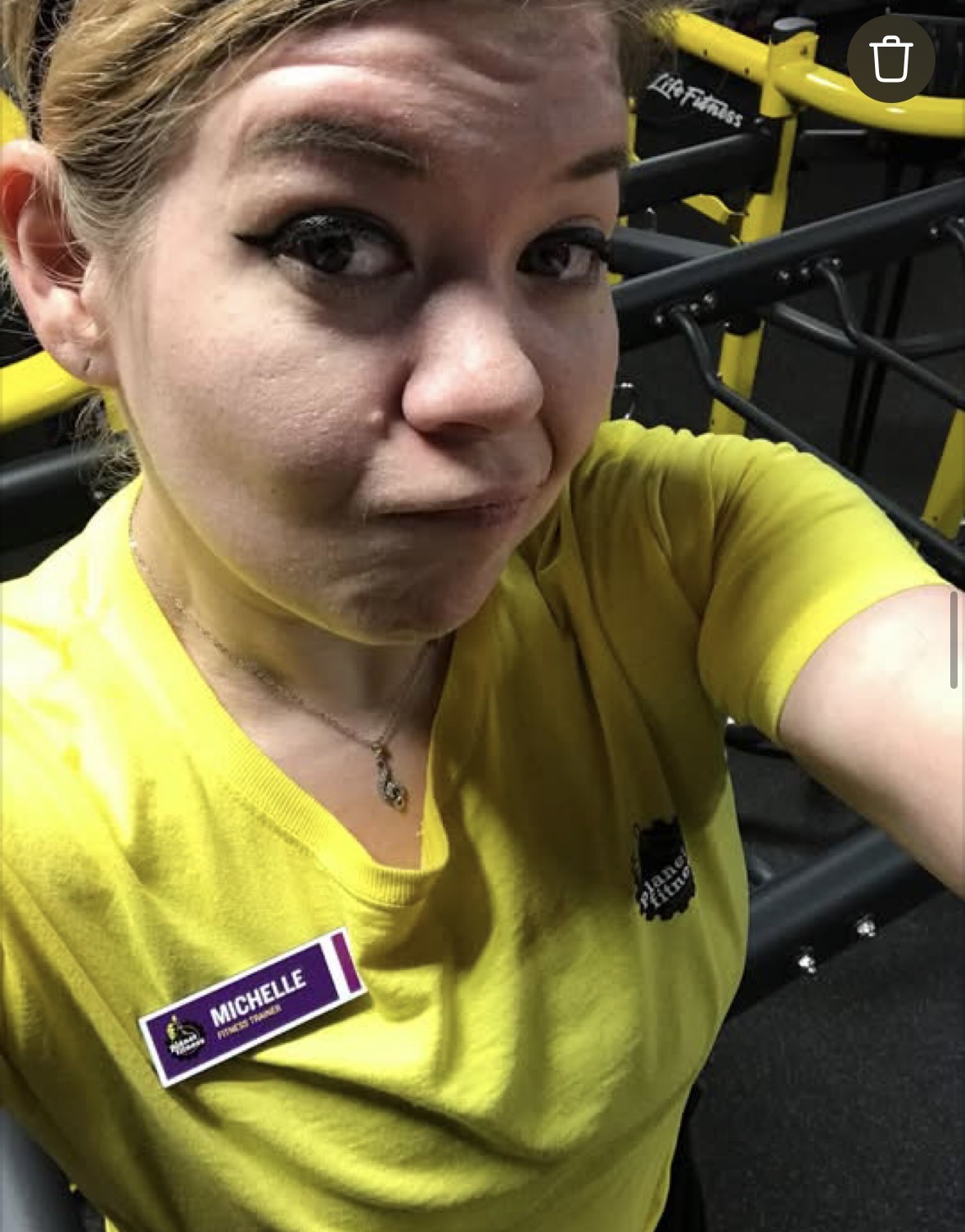 Michelle wearing her yellow Planet Fitness staff shirt at the gym.